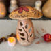This shows a handmade mushroom decoration. Made from a gourd, it has a fern carved in the stock and wood burned bee artwork on top. 